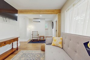 A living room with a sofa, a wooden bench, a chair, and a rug. - Beautiful house w/ mountain view, balcony, grill, central a/c, close to skiing (Ludlow)