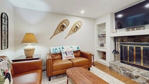 Un salon avec un canapé en cuir, une table basse en bois, une cheminée et des éléments décoratifs fixés au mur.