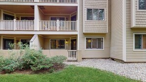Un immeuble à plusieurs étages doté de balcons, d’un petit jardin et d’une allée gravillonnée.