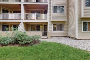 A multi-story building with balconies, a small garden area, and a gravel driveway. - Updated ground floor condo w/ patio, fireplace, ski locker, door to door shuttle (Stratton)