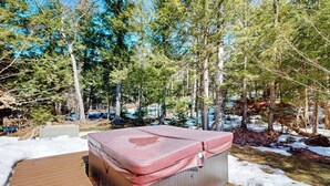 A hot tub in a forested area with snow on the ground. - Delightful house w/ hot tub, wrap-around deck, ping-pong-pool table, fireplaces (Ludlow)
