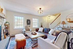 A living room with a fireplace, a sofa, a coffee table, and a staircase.