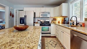 A kitchen with white cabinets, a granite countertop, a stove, a microwave, and a dishwasher. - Delightful house w/ hot tub, wrap-around deck, ping-pong-pool table, fireplaces (Ludlow)