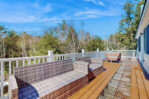 A wooden deck with wicker furniture and a covered area.