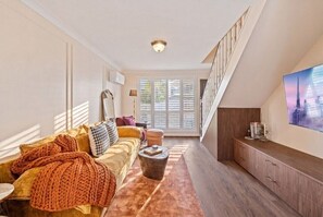 Ein Wohnzimmer mit einer Couch, einem Couchtisch und einem Fernseher an der Wand.