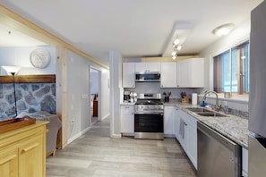 A modern kitchen with white cabinets, stainless steel appliances, and a granite countertop. - Dog-friendly home w/ WiFi, private washer/dryer, and electric fireplaces (West Dover)