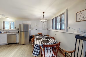 A modern kitchen with a stainless steel refrigerator, a dining table with checkered tablecloths, and wooden chairs. - Dog-friendly home w/ WiFi, private washer/dryer, and electric fireplaces (West Dover)