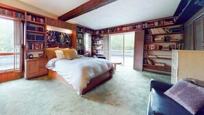Quarto com uma cama grande, estantes embutidas e vista pela janela.