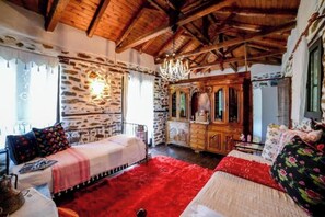 A rustic room with stone walls, wooden furniture, and a red carpet. - Filoxenia-Drakeia (Drakia)