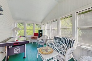 A sunroom with a pool table, a sofa, and wicker chairs. - Spacious village house, dog-friendly, patio, fireplace, a/c, air hockey, w/d (Manchester)
