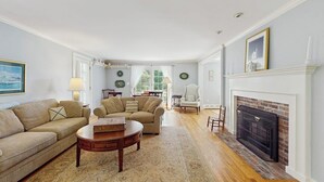 Ein Wohnzimmer mit zwei Sofas, einem Kamin und einem Essbereich im Hintergrund.