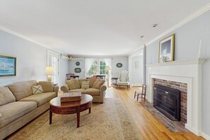 A living room with two sofas, a fireplace, and a dining area in the background. - Spacious village house, dog-friendly, patio, fireplace, a/c, air hockey, w/d (Manchester)