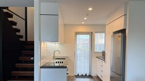 A compact kitchen with a built-in oven, a refrigerator, and a microwave. - Stadium Gatehouse - Bookahome (Central City Christchurch)