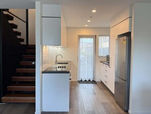 Eine kompakte Küche mit Einbauofen, Kühlschrank und Mikrowelle.