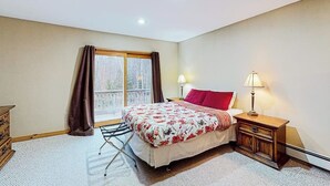 A bedroom with a bed, a window with curtains, a nightstand with a lamp, and a dresser. - Exquisite home with fireplace, balcony, fast WiFi, jetted tub & washer/dryer (West Dover)