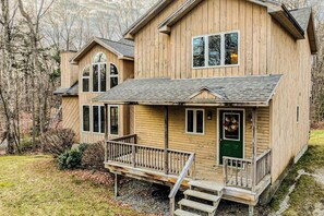 Eine Holzhütte mit Veranda, einer grünen Tür und einer kleinen Treppe, die zum Eingang führt.