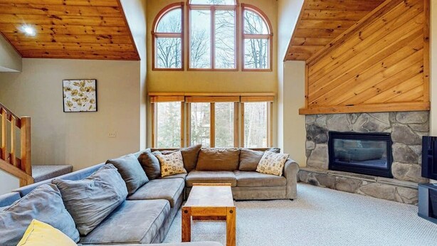 A spacious living room with a large sectional sofa, a fireplace, and a stone accent wall. - Exquisite home with fireplace, balcony, fast WiFi, jetted tub & washer/dryer (West Dover)