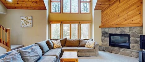 A spacious living room with a large sectional sofa, a fireplace, and a stone accent wall.