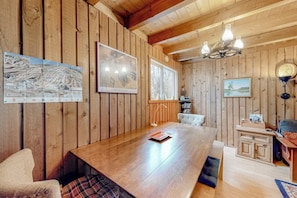 Una habitación con paneles de madera, una mesa grande, un candelabro, cuadros enmarcados y un reloj.