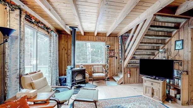 Ein Holzhütten-Innenraum mit Kamin, Fernseher und einer Treppe.