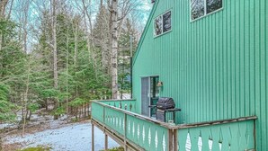 Eine grüne Holzhütte mit einer Terrasse, umgeben von Bäumen.