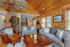 Ein Holzinterieur mit einer Couch, einem Sessel und einem Couchtisch.