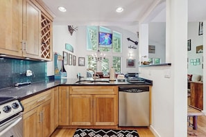 A kitchen with wooden cabinets, a dishwasher, a stove, and a chandelier. - Ski-in/ski-out townhouse w/ trail access, fireplace, balcony, pool, hot tub (Stratton)