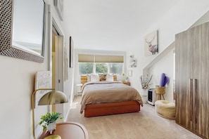 A bedroom with a bed, bedside tables, a wardrobe, a window, and a mirror. - Ski-in/ski-out townhouse w/ trail access, fireplace, balcony, pool, hot tub (Stratton)