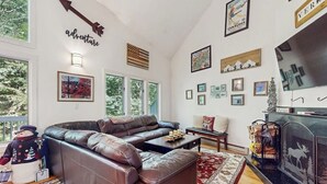 Ein Wohnzimmer mit einem Ecksofa, einem Kamin und verschiedenen gerahmten Bildern an den Wänden.