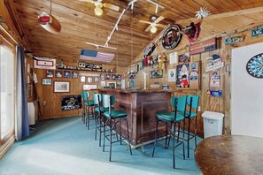 Eine Bar mit Holzwänden, einer Theke und mehreren Stühlen.