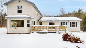 Ein zweistöckiges Haus mit überdachter Veranda und einem schnee bedeckten Hof.