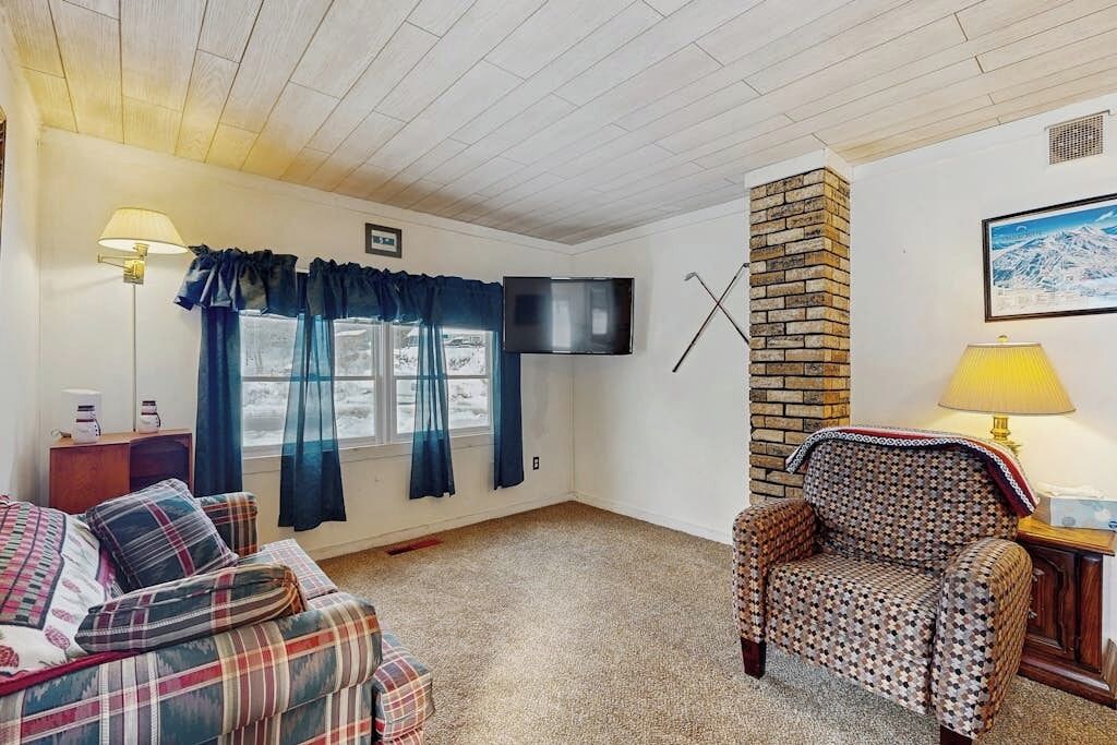 A cozy room with a television, a fireplace, a sofa, and a patterned armchair.