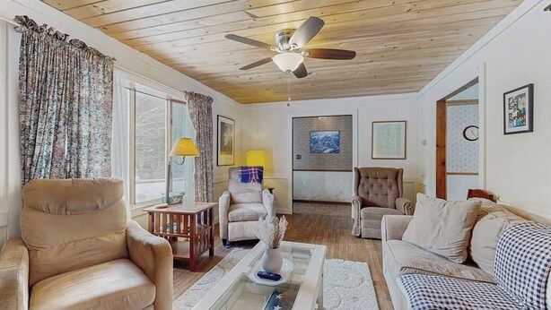 Ein Wohnzimmer mit Deckenventilator, einer Couch, einem Sessel, einem Couchtisch und einer Lampe.