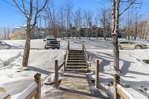 Ein verschneiter Weg führt zu einem Gebäude mit einer Holztreppe.