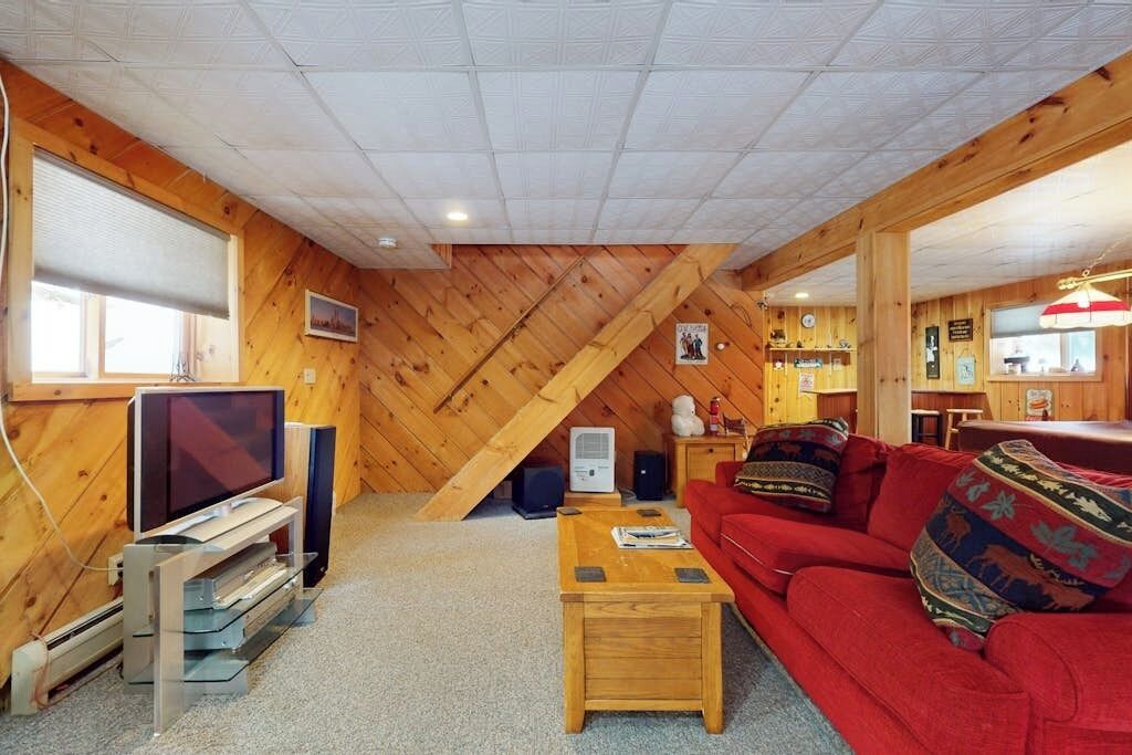 Una habitación acogedora con techo de madera, televisión, sofá y una pequeña mesa.