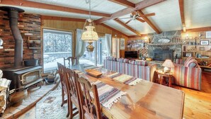 Ein rustikales Interieur mit Kamin aus Stein, Esstisch aus Holz und einer gemütlichen Sitzecke.
