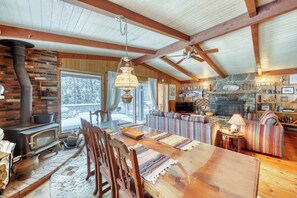 Ein rustikales Interieur mit Kamin aus Stein, Esstisch aus Holz und einer gemütlichen Sitzecke.