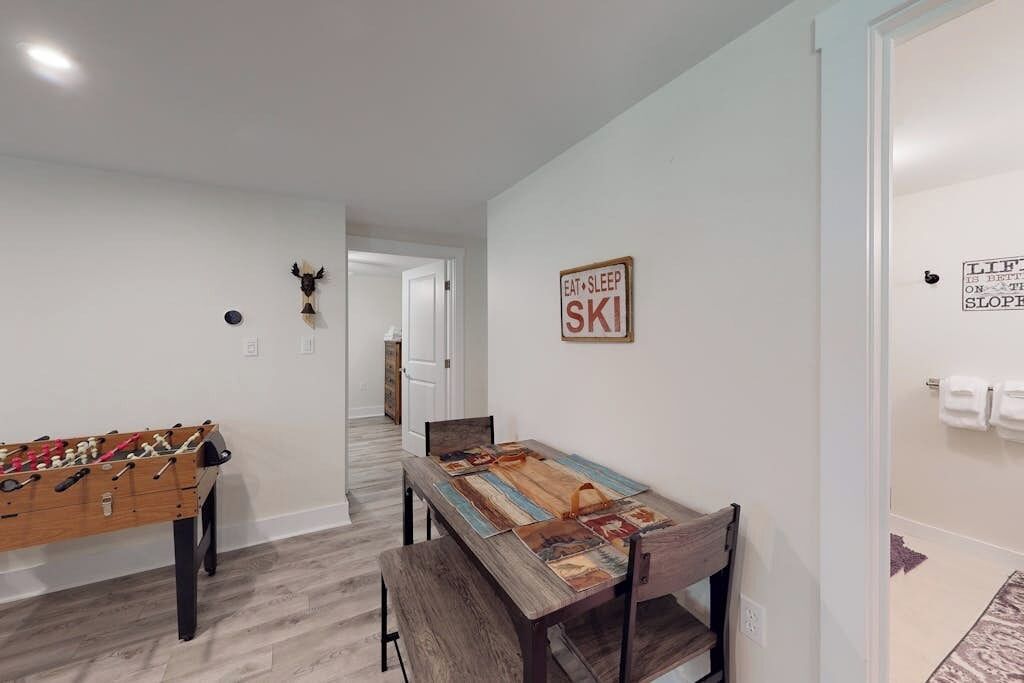 A room with a foosball table, a small table with chairs, and a wall sign that says 'EAT SLEEP SKI'.