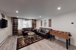A living room with a sofa, a foosball table, a coffee table, and a patterned rug.