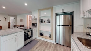 Una cocina moderna con armarios blancos, un refrigerador de acero inoxidable y una encimera de granito.