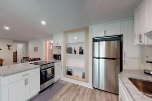 A modern kitchen with white cabinets, a stainless steel refrigerator, and a granite countertop.