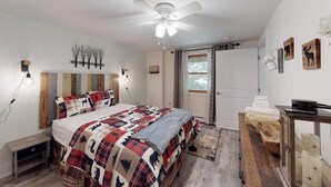 Un dormitorio con cama, ventilador de techo, mesita de noche, cómoda y puerta con vistas.