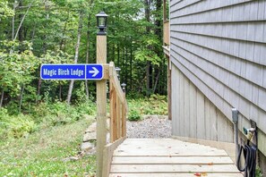 A wooden deck leading to a lodge with a directional sign for Magic Birch Lodge.