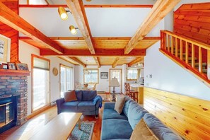 A cozy living room with a fireplace, wooden beams, a staircase, and a dining area. - Forest Home with Shared Pool & Hot Tub, WiFi, & Washer/Dryer - One Small Dog OK (Wilmington)