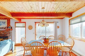 Un comedor con una mesa y sillas de madera, un candelabro y vistas a través de un gran ventanal.
