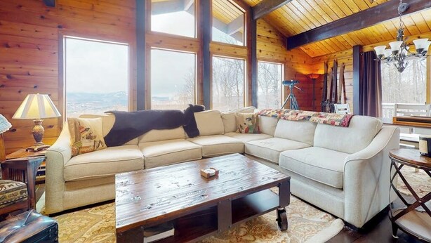 A wooden interior with a large sofa, a coffee table, and a chandelier. - Inviting mountain view home with game room, balcony & W/D (West Dover)