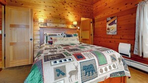 A wooden cabin bedroom with a quilted bedspread, a mounted poster, and a heater. - Inviting mountain view home with game room, balcony & W/D (West Dover)