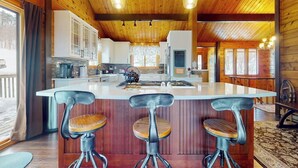 A wooden interior with a central island, bar stools, and pendant lighting. - Inviting mountain view home with game room, balcony & W/D (West Dover)