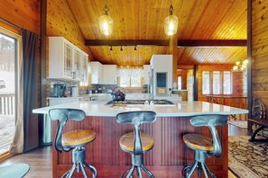 Ein Holzinterieur mit einer zentralen Kücheninsel, Barhocker und Pendelleuchten.