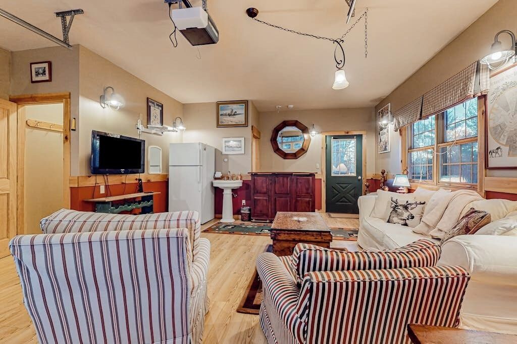A cozy living room with striped sofas, a television, a fireplace, and a dining area.